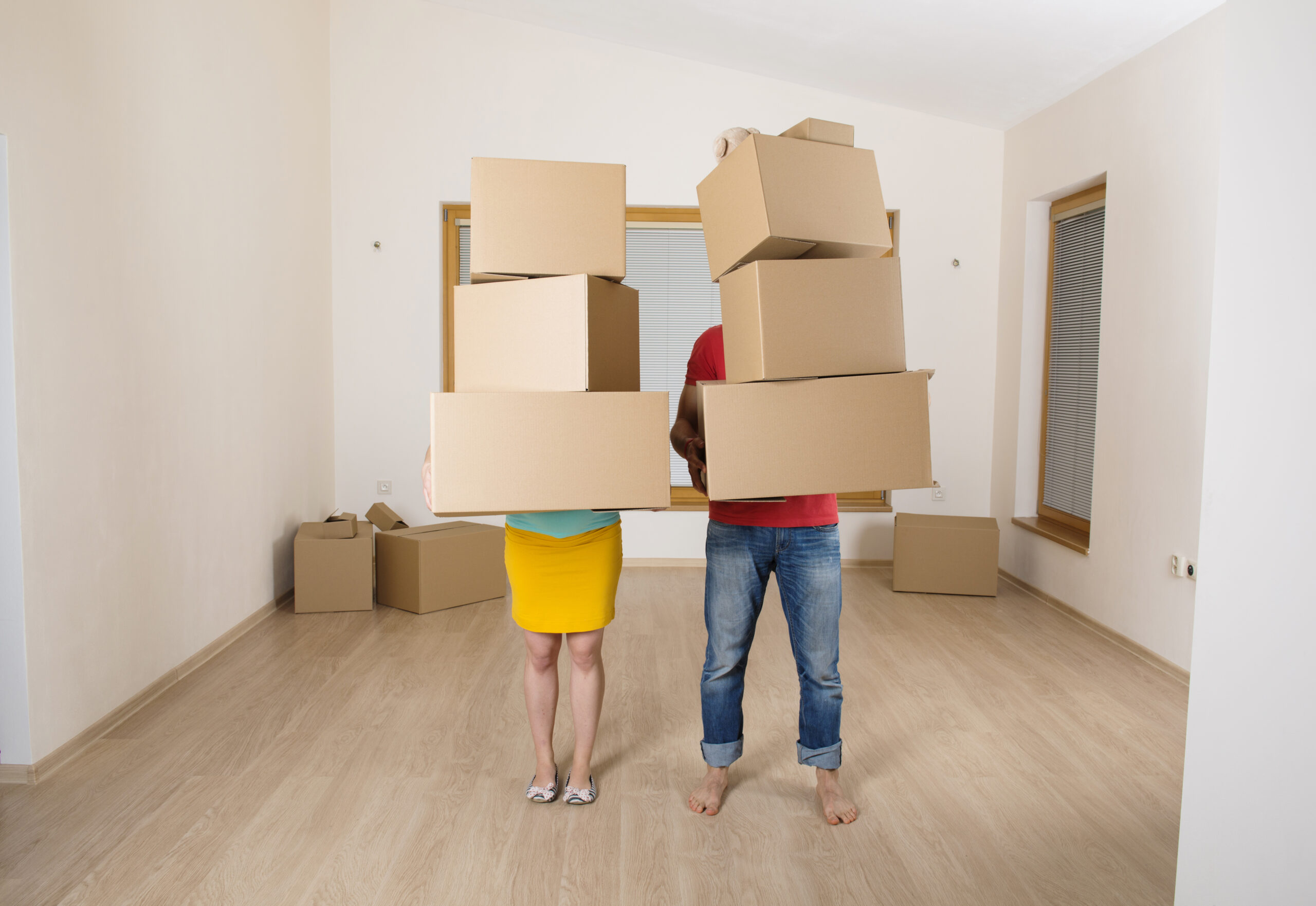 Young couple is moving into new house with lot of boxes. Woman is pregnant.